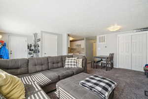 Carpeted living area with a textured ceiling and baseboards