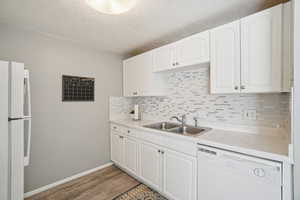 Kitchen with white appliances, light countertops, white cabinetry, dark wood-type flooring, and a textured ceiling