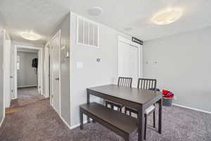 Dining space featuring dark carpet and a textured ceiling