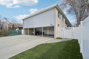 View of side of home featuring a gate, a carport, and concrete driveway