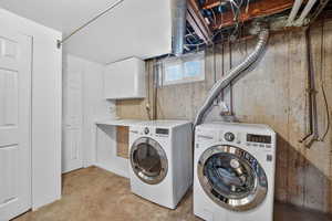 Laundry room featuring cabinet space, unfinished concrete flooring, and washer and dryer