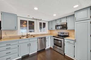 Kitchen featuring light countertops, stainless steel appliances, recessed lighting, dark wood-style floors, and a textured ceiling