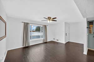 Unfurnished living room featuring ceiling fan, dark wood-style flooring, and a water view