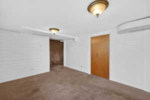 Unfurnished bedroom with carpet floors and wooden walls