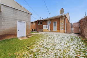 Rear view of house featuring a gate, a chimney, and brick siding