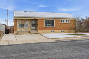 View of front facade featuring entry steps, roof with shingles, stone siding, and brick siding