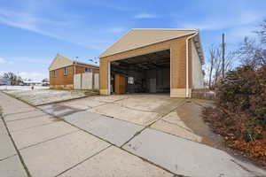 View of property exterior with brick siding, an outdoor structure, and a garage