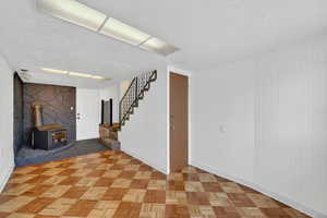Basement featuring a textured ceiling, a wood stove, and parquet flooring