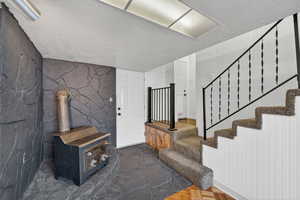 Staircase featuring a wood stove, a textured ceiling, and parquet flooring
