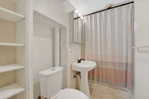 Full bath with toilet and a shower with curtain