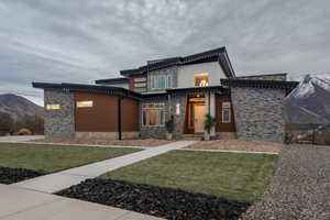 Contemporary home with stone siding, a mountain view, and a front yard