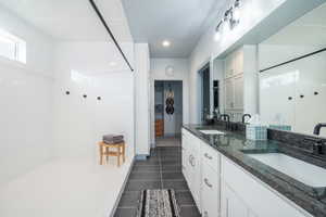 Bathroom featuring double vanity, a walk in shower, and dark tile patterned floors