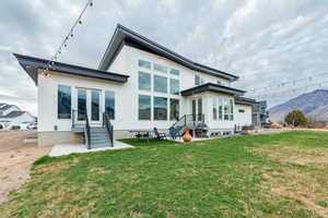 Back of property with a patio area, a yard, stucco siding, and a mountain view