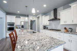 Kitchen featuring a breakfast bar, white cabinets, light stone counters, stainless steel appliances, and decorative backsplash