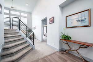 Stairs featuring a ceiling fan, wood finished floors, a high ceiling, and recessed lighting