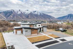 View of front of property with stone siding, a mountain view, a residential view, concrete driveway, and an attached garage
