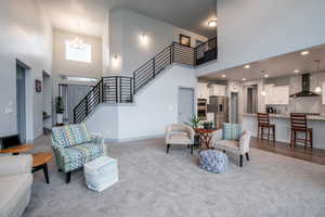 Living area with a high ceiling, hanging lights, and carpet floors