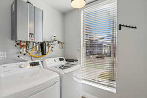 Laundry area with tankless water heater and washing machine and dryer