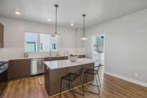 Kitchen featuring a breakfast bar area, modern cabinets, stainless steel appliances, dark wood finish cabinets, and dark wood-style flooring