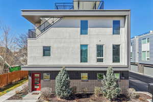 View of front of property featuring brick siding, a balcony, and stucco siding