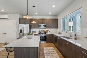 Kitchen featuring a center island, stainless steel appliances, a breakfast bar area, pendant lighting, and dark wood finish cabinetry