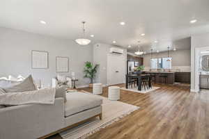 Living room featuring light wood-style flooring, recessed lighting, and a wall mounted mini split