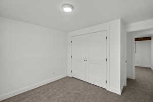 Unfurnished bedroom with dark colored carpet and a closet
