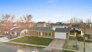 Traditional-style home with a residential view, concrete driveway, an attached garage, brick siding, and roof with shingles