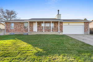 Single story home with covered porch, a chimney, driveway, a garage, and brick siding