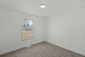 Spare room featuring baseboards and carpet