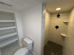 Bathroom featuring a shower stall and light marble finish floors