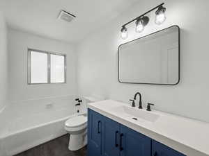 Bathroom with a garden tub, vanity, and dark wood-type flooring