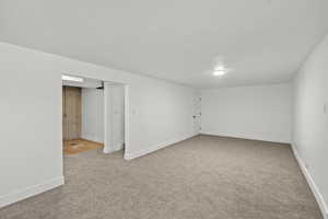 Spare room with baseboards and light colored carpet
