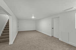 Finished basement with stairway and light colored carpet