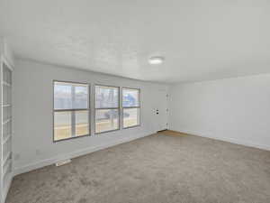 Spare room with baseboards and light colored carpet