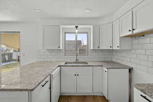 Kitchen with white cabinetry, dishwasher, a peninsula, and recessed lighting
