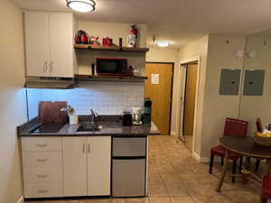 Kitchen featuring stainless steel fridge, electric induction panel,  microwave, decorative backsplash