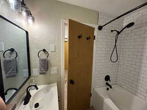 Bathroom featuring a textured wall, vanity, and tub / shower combination