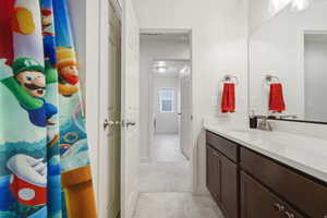 Bathroom with vanity, a shower with curtain, and light colored carpet