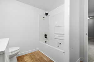 Bathroom with light wood-style flooring, vanity, and bathing tub / shower combination