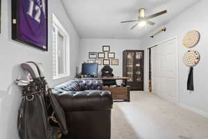 Carpeted bedroom/office with a ceiling fan