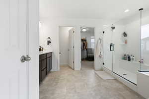 Full master bathroom featuring vanity, a shower stall, and a walk in closet