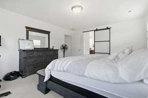 Master Bedroom with a barn door, ensuite bathroom, and light carpet