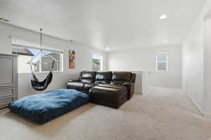 Living area with light carpet and recessed lighting