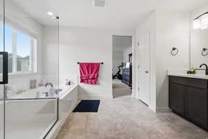 Ensuite master bathroom featuring vanity and a bath