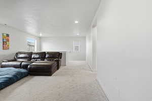 Living area with light carpet and recessed lighting