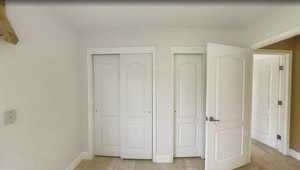 Unfurnished bedroom featuring baseboards and two closets