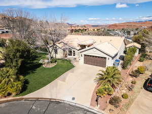 View of front facade with stucco siding, a garage, concrete driveway, a front yard, and a tiled roof