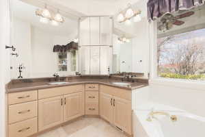 Bathroom featuring double vanity, a bath, light tile patterned floors, and suspended lighting