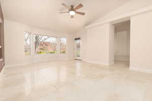 Empty room featuring a ceiling fan and vaulted ceiling